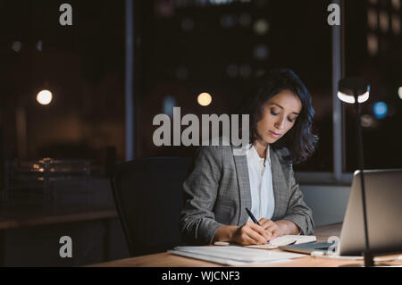 Young businesswoman working in her office at night Stock Photo