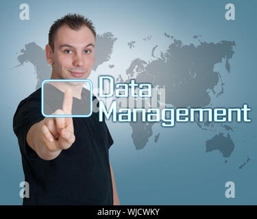 Young man press digital Data Management button on interface in front of him Stock Photo