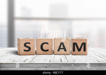 The word scam made of wooden blocks on a table in a bright office room Stock Photo