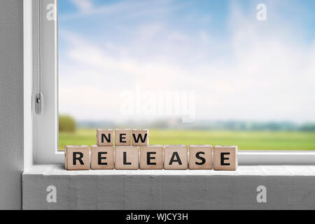 New release sign in a window on a sill with a view to green fields and blue sky Stock Photo