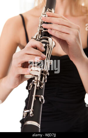 Beautiful young woman playing clarinet over black background Stock Photo