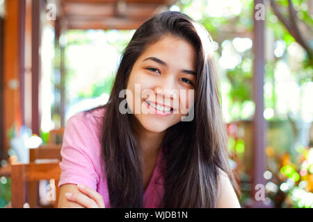 Biracial teen girl relaxing outdoors on sunny veranda Stock Photo