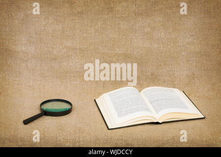 Open book and magnifier on canvas background - a still-life Stock Photo ...