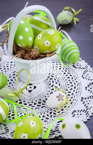 Collection of four hand decorated colourful green Easter eggs with different patterns displayed in straw, close up view Stock Photo