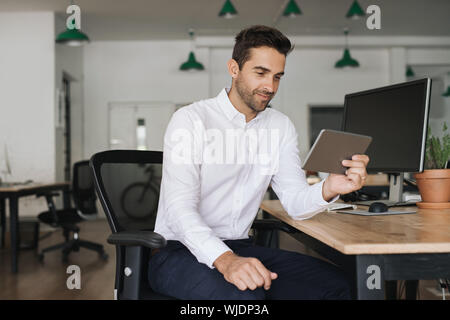 Smiling businessman working on a tablet in an office Stock Photo