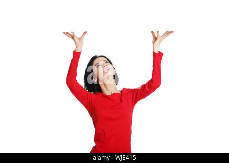 Smiling young woman is holding something abstract above her head. Happy girl with raised hands. Isolated on white background. Stock Photo