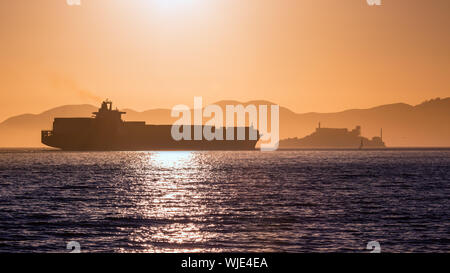 Alcatraz island penitentiary at sunset and merchant ship in san Francisco California USA Stock Photo