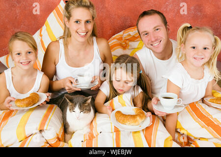 Family and cat having breakfast in bed Stock Photo