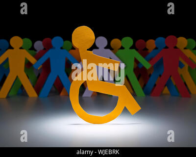 A disable paper figure stands under the spotlight on his wheelchair. Stock Photo