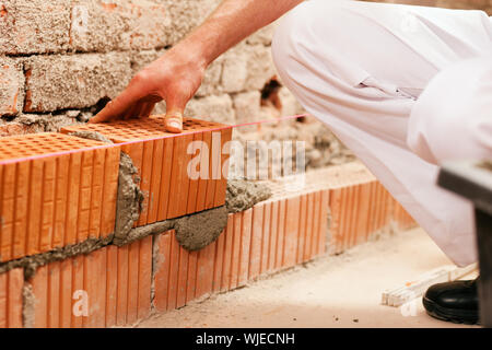 bricklayer with brick on construction site Stock Photo