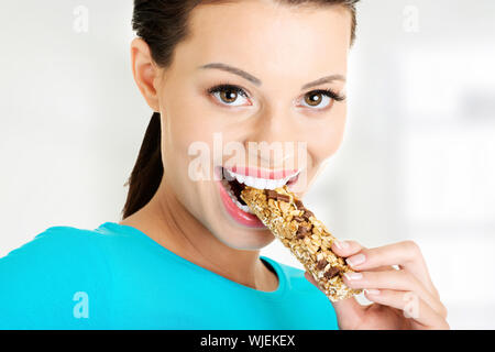 Young woman eating Cereal candy bar, isolated on white Stock Photo