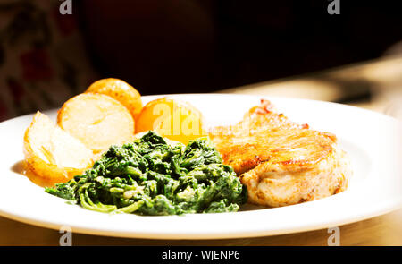 Fresh coocked food on a plate with spinach saland, potatoes and meat. Stock Photo