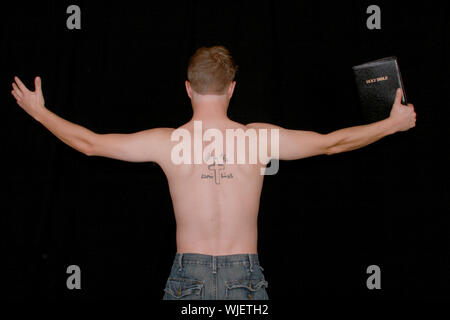 A man preaching with a crucifix and aramiac writing tattooed on his back. Stock Photo