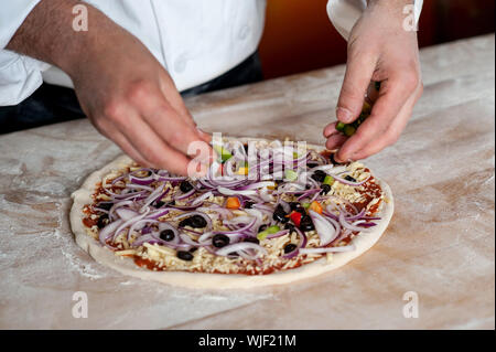 Chef spreading onion on pizza base Stock Photo