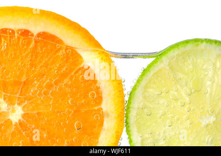 Orange and lime slices in water with air bubbles on white background Stock Photo
