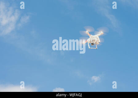 drone against the blue sky. quadcopter shoots the plot from above. Remote quadrocopter flies across the blue sky. Stock Photo