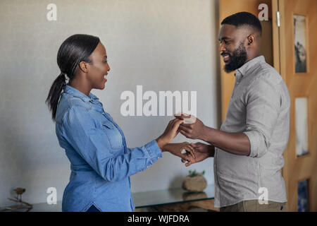 Smiling young African American couple dancing in their living room Stock Photo