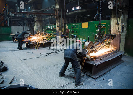 Industrial workers with work tool. Big chainsaw in hands at steel factory Stock Photo