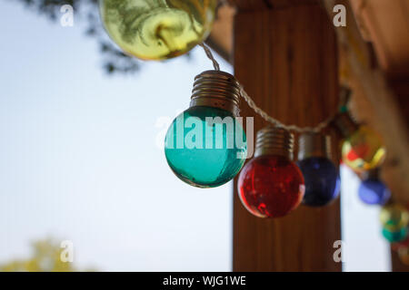 Close up of a garland of multi-colored light bulbs, decor of the outdoor veranda, selective focus Stock Photo