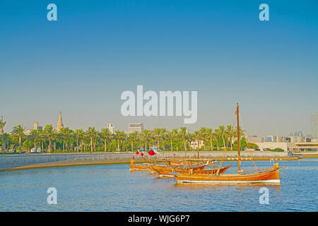 Dhow moored in bay with old town part of Doha city in background with spiral structure of old mosque on skyline. Stock Photo