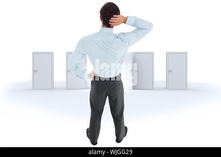 Thinking businessman scratching head against door opening revealing bright light Stock Photo