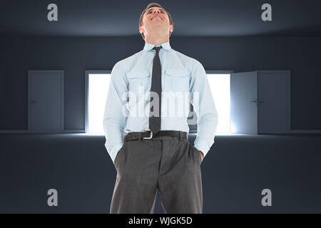 Happy businessman standing with hands in pockets against doors opening revealing light Stock Photo