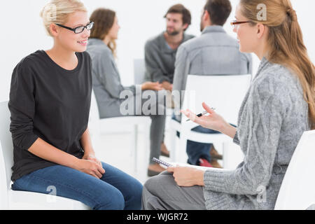 Group therapy session in circle with therapist and client in foreground Stock Photo