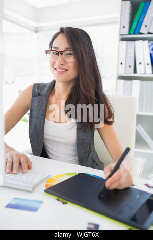 Portrait of a smiling casual female photo editor using graphics tablet in a bright office Stock Photo