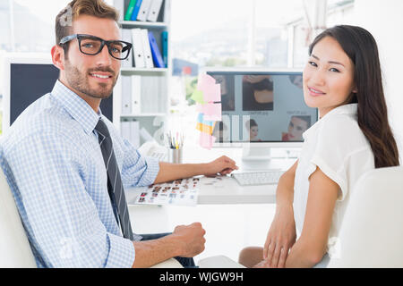 Rear view of casual photo editors working on computer in a bright office Stock Photo