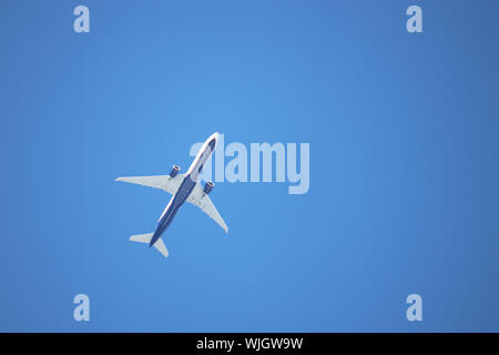 Airplane flying in the clear blue sky, bottom view. Commercial plane taking off Stock Photo