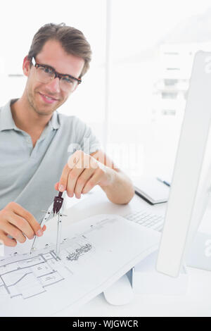 Smiling young man using compass on design Stock Photo