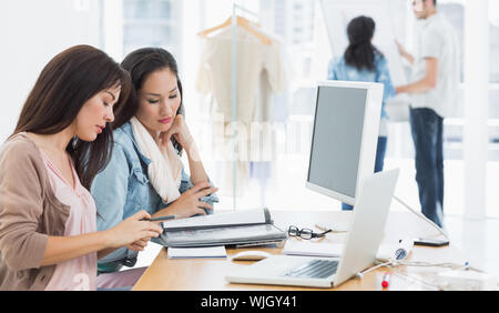 Two casual female artists working at desk in the creative office Stock Photo