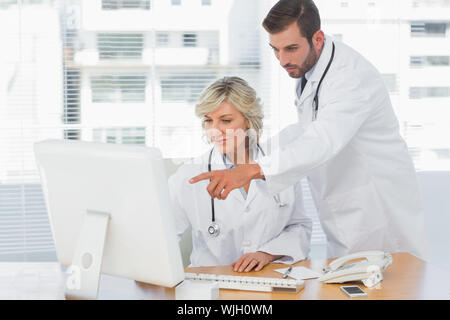 Two concentrated doctors using computer at medical office Stock Photo