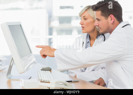 Two concentrated doctors using computer at medical office Stock Photo
