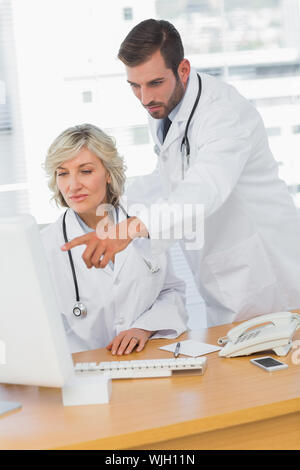 Two concentrated doctors using computer at medical office Stock Photo