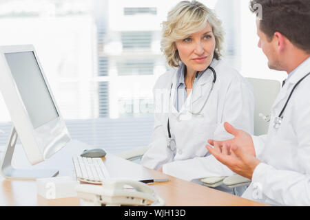 Two concentrated doctors discussing something by computer at medical office Stock Photo