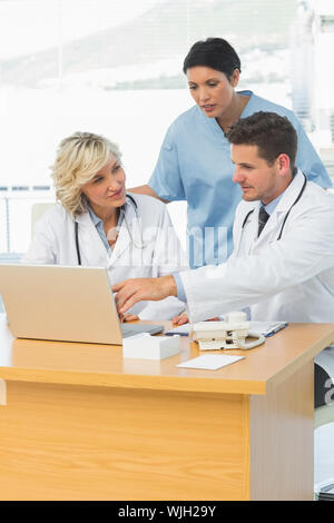 Three concentrated doctors using laptop together at the medical office Stock Photo