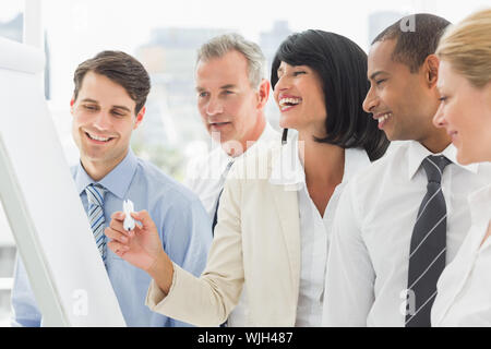 Colleagues watching laughing businesswoman write on whiteboard in the office Stock Photo