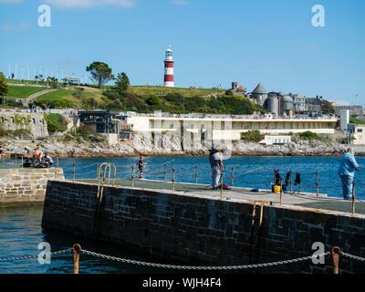Anglers on West Hoe pier, Plymouth, Devon, UK, against a backdrop of Plymouth Hoe and Smeaton's Tower Stock Photo