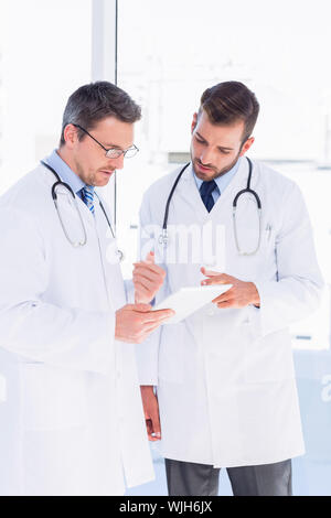 Concentrated two male doctors using digital tablet in a bright medical office Stock Photo