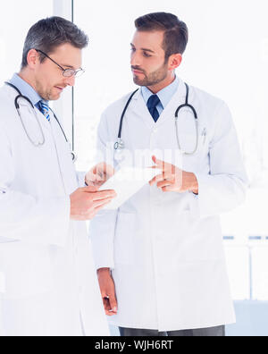Concentrated two male doctors using digital tablet in a bright medical office Stock Photo