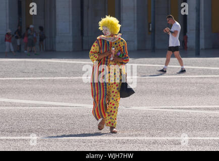 An off duty street performing clown taking some down time in Lisbon's Praça do Comércio Stock Photo