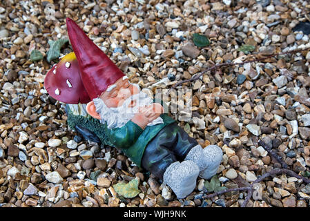 Garden gnome sleeping with his head resting on a toadstool. Stock Photo