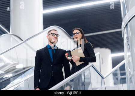 Young businesspeople standing on a staircase and talking at modern office building Stock Photo