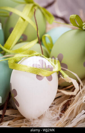 Collection of four hand decorated colourful green Easter eggs with different patterns displayed in straw, close up view Stock Photo