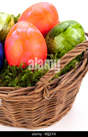Rustic wicker basket of brightly coloured hand-painted traditional Easter Eggs with a marbled pattern nestling in a bed of green moss, high angle view Stock Photo