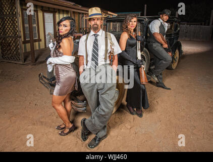 1920s gangsters with guns next to antique automobile Stock Photo