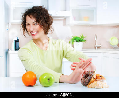 Dieting concept. Young Woman choosing between Fruits and Sweets Stock Photo