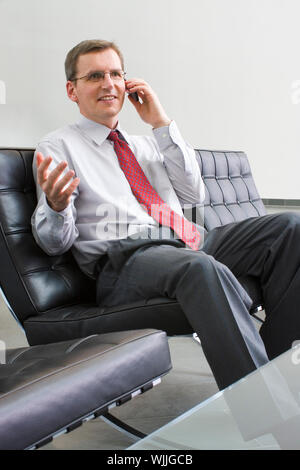Businessman or politician talking on cell phone while sitting in a chair of leather Stock Photo