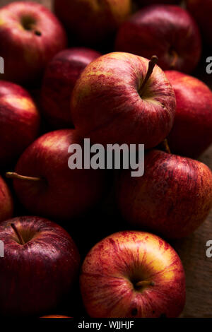 Deep red Royal Gala apples on a rustic wooden table with soft lighting Stock Photo